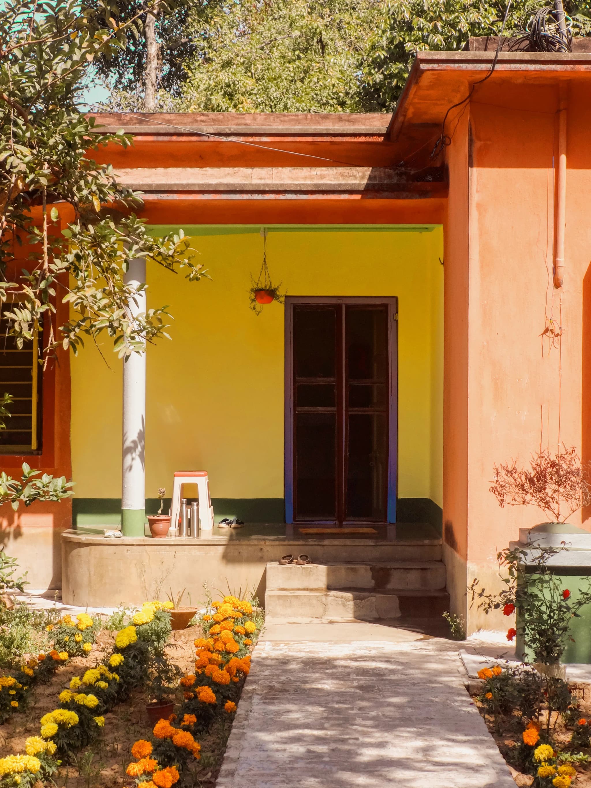 House entrance with a yellow and orange front, marigold beds and a paved path