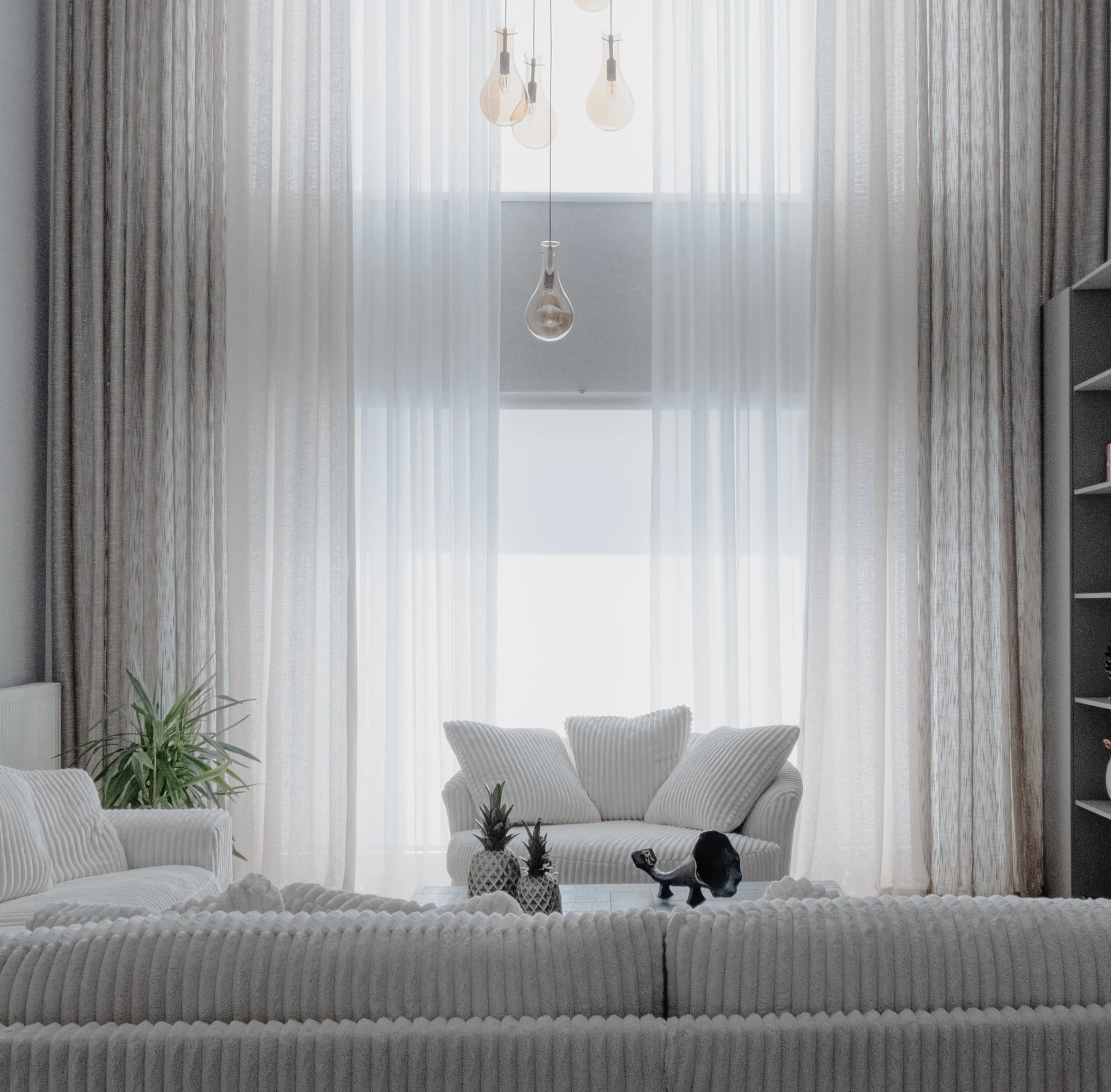 Airy white living room with floor-to-ceiling sheer curtains and white sofas