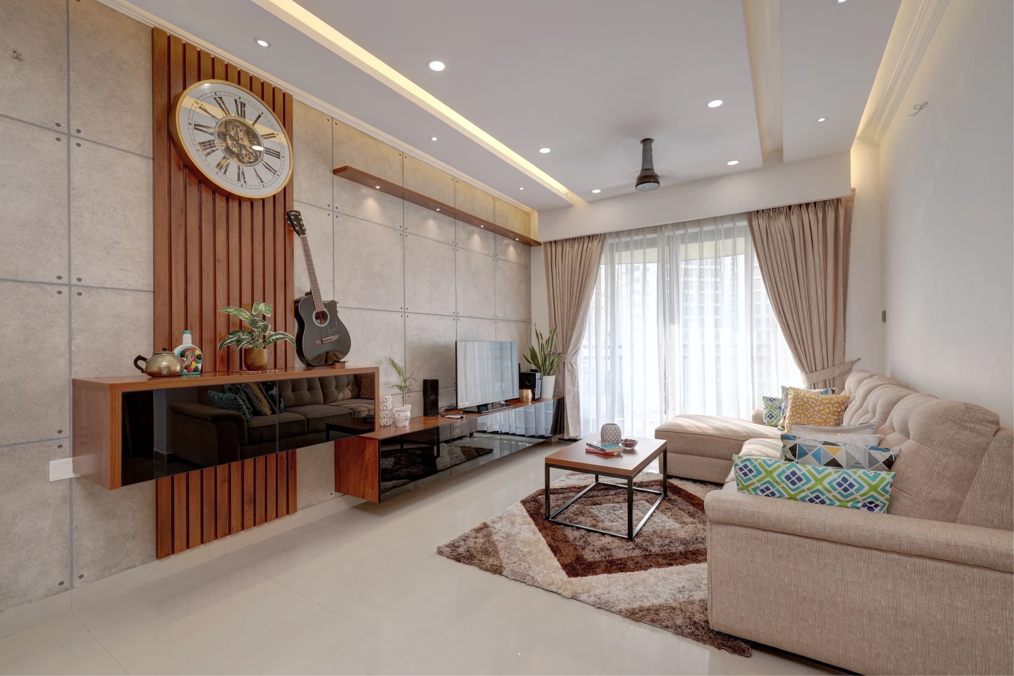 Living room with warm grey walls, a wooden slat panel, a wall clock and a beige sofa