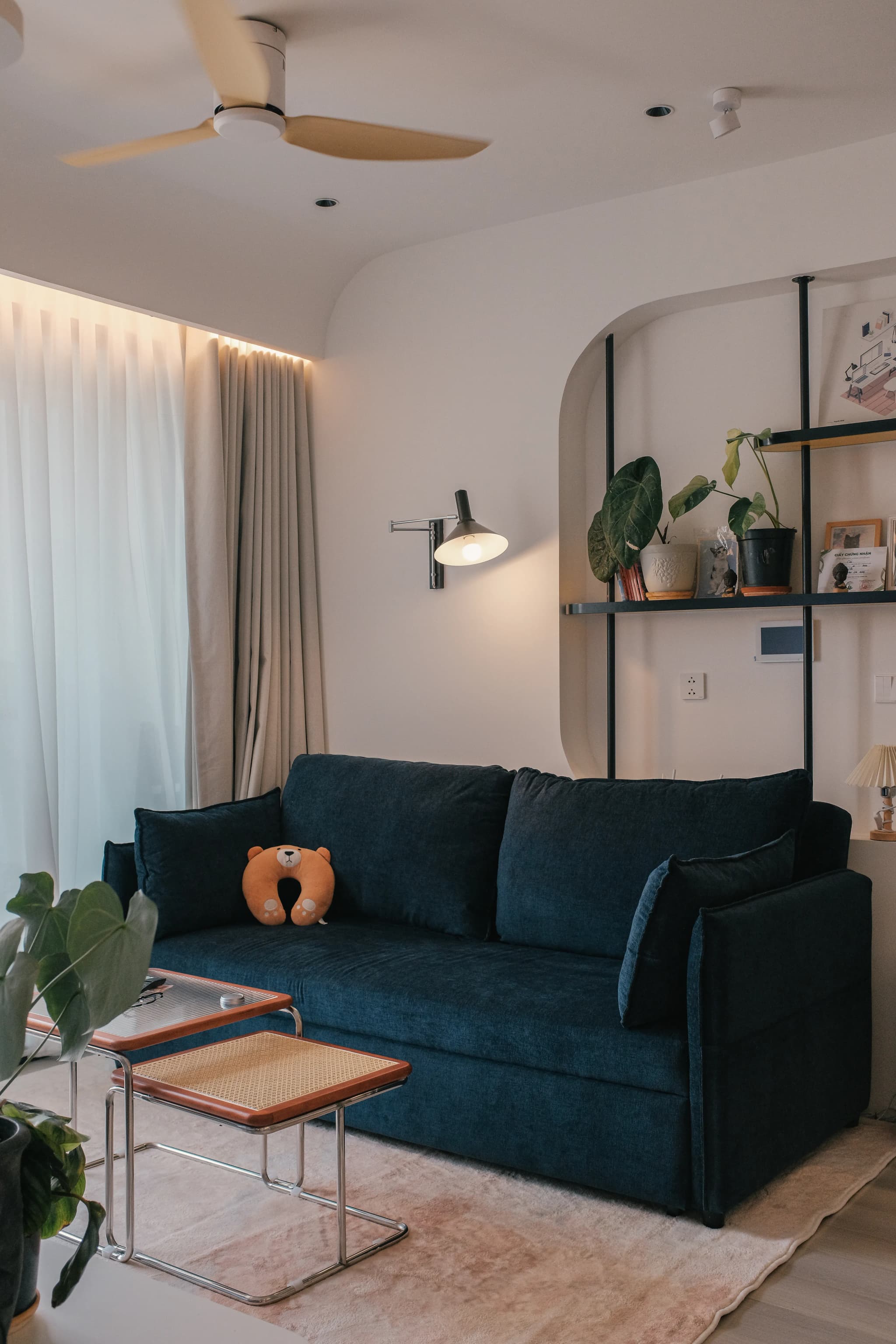 Living room with warm white walls, a navy sofa and open shelving