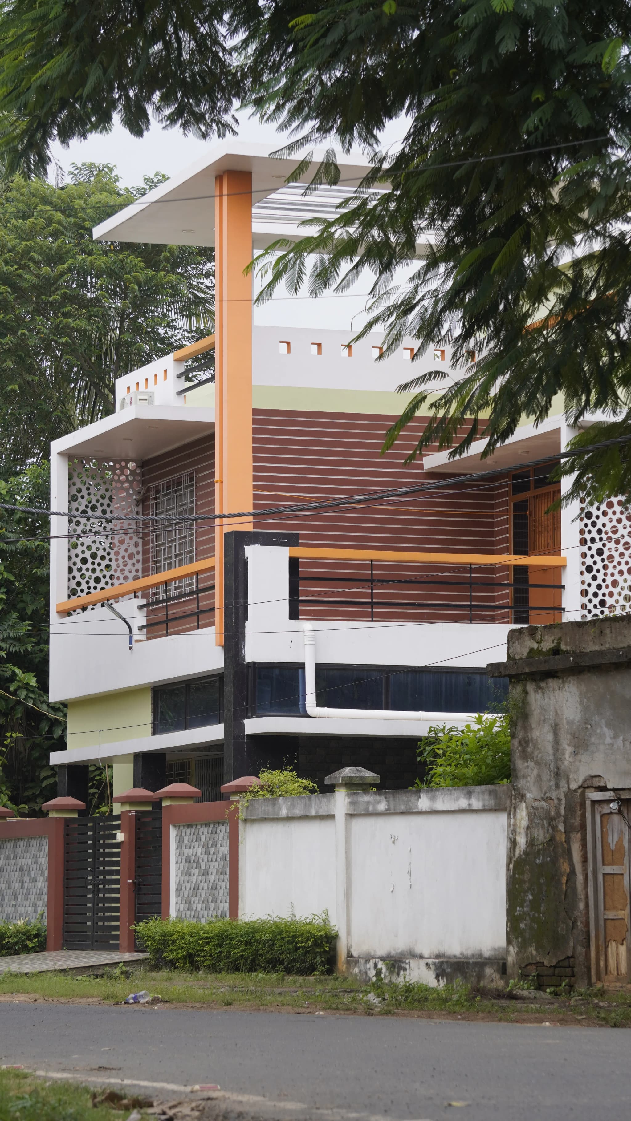 Two-storey modern house with white walls, wood-look panels and a carved screen on the balcony
