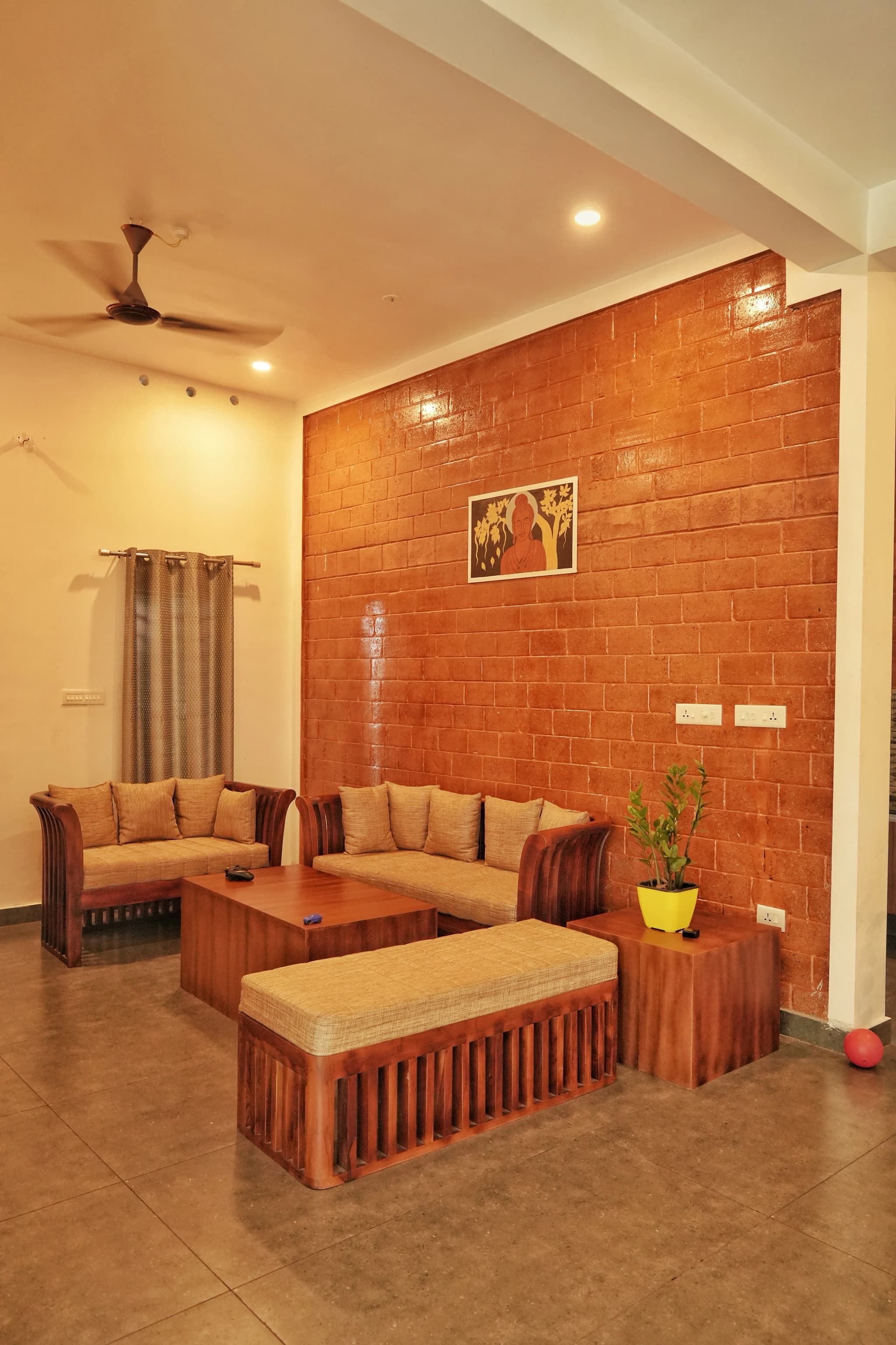 Living room with an orange brick accent wall, wooden sofas and warm ceiling lights