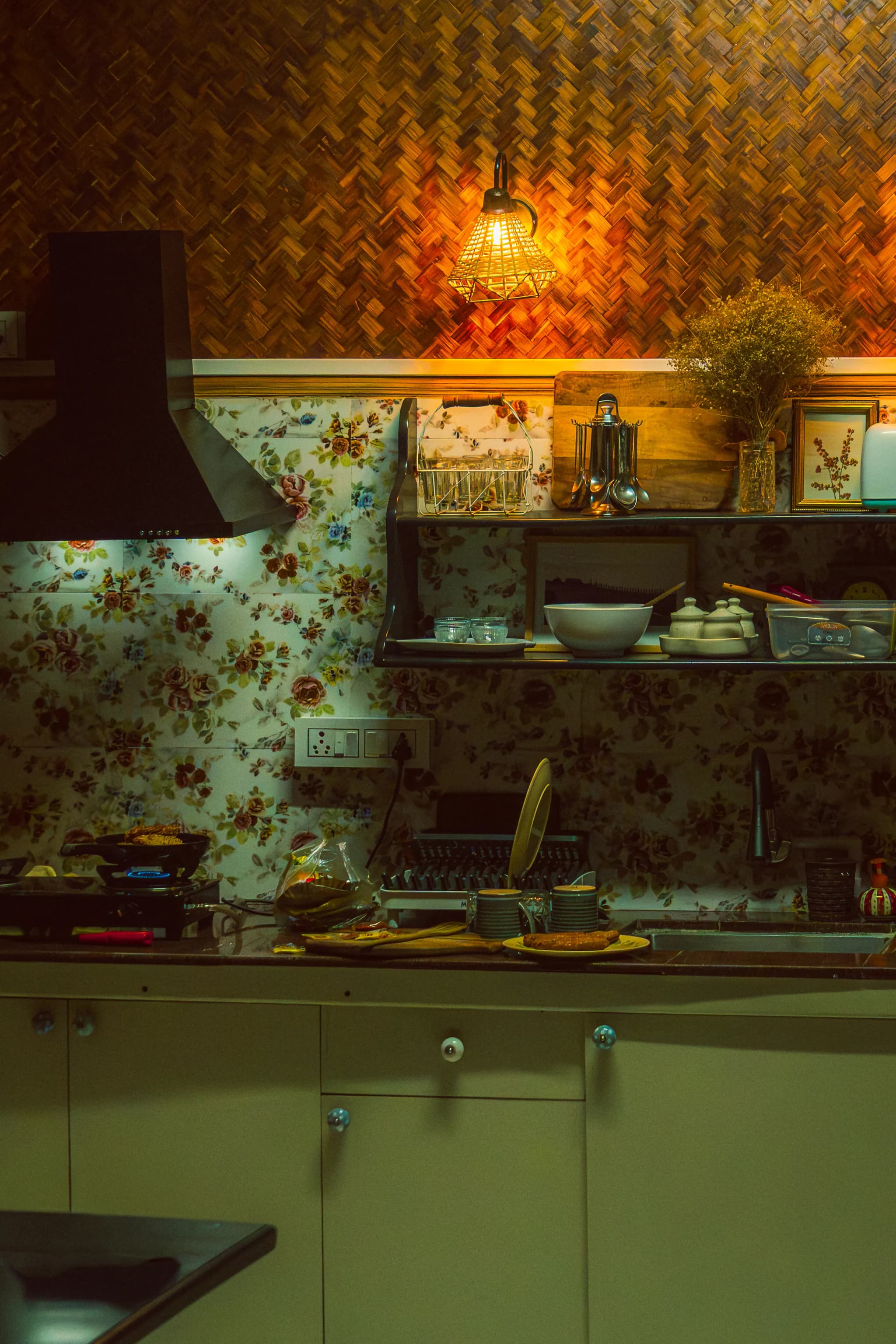 Kitchen with sage-green cabinets, a floral tiled wall and warm hanging lights