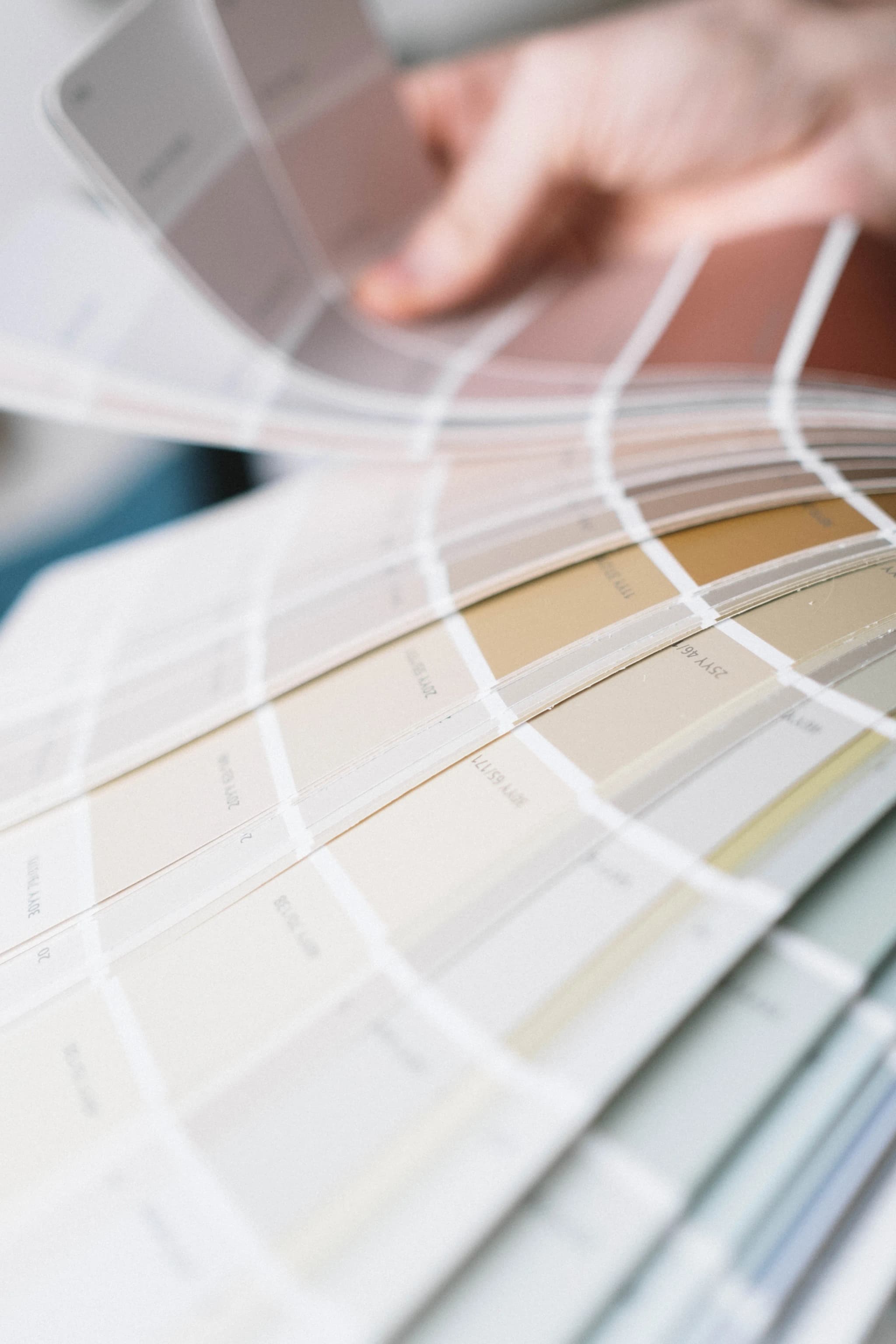 Hand leafing through a fan deck of neutral paint shade cards