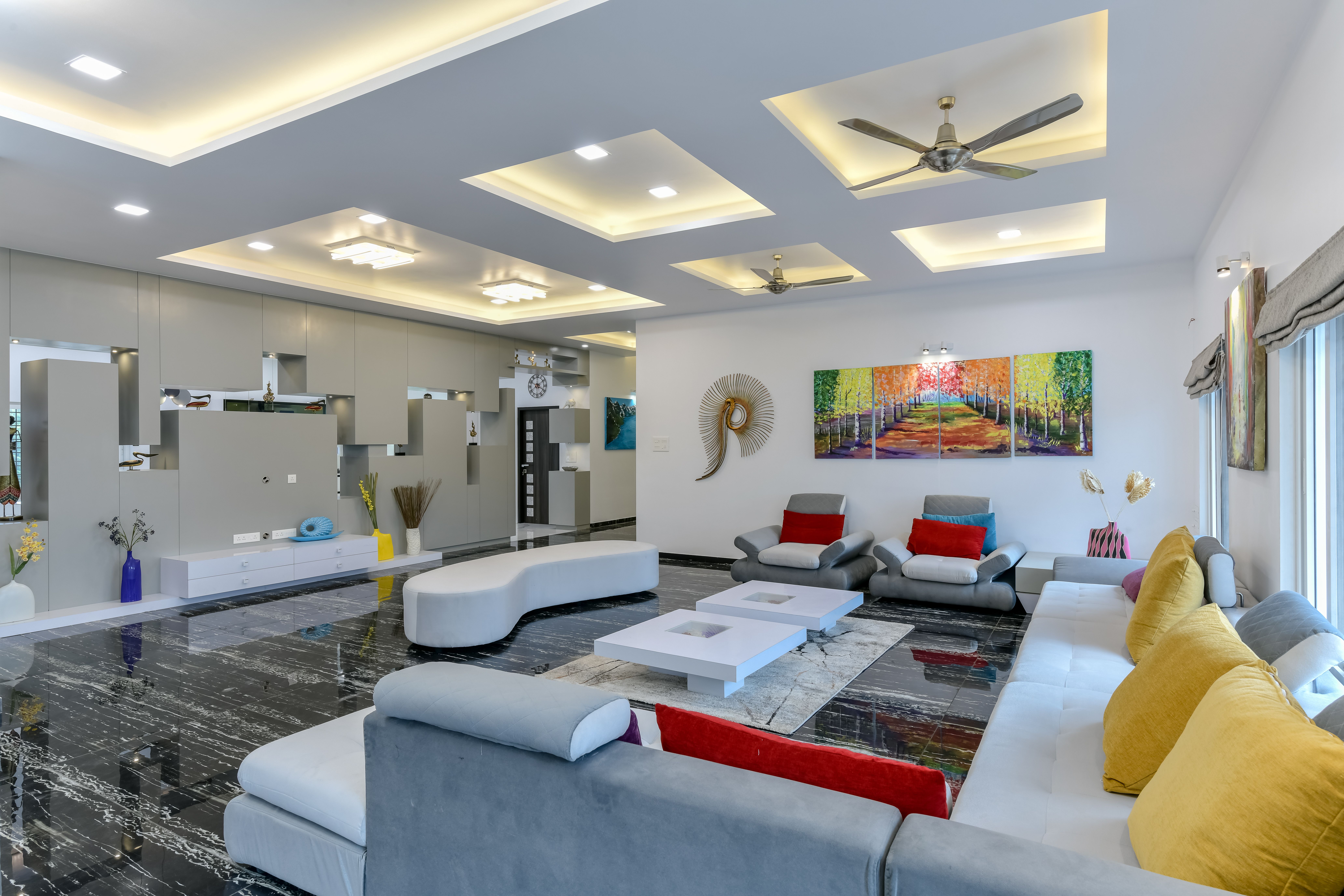 Bright living room with a coffered ceiling, grey sofas, yellow cushions and colourful wall art